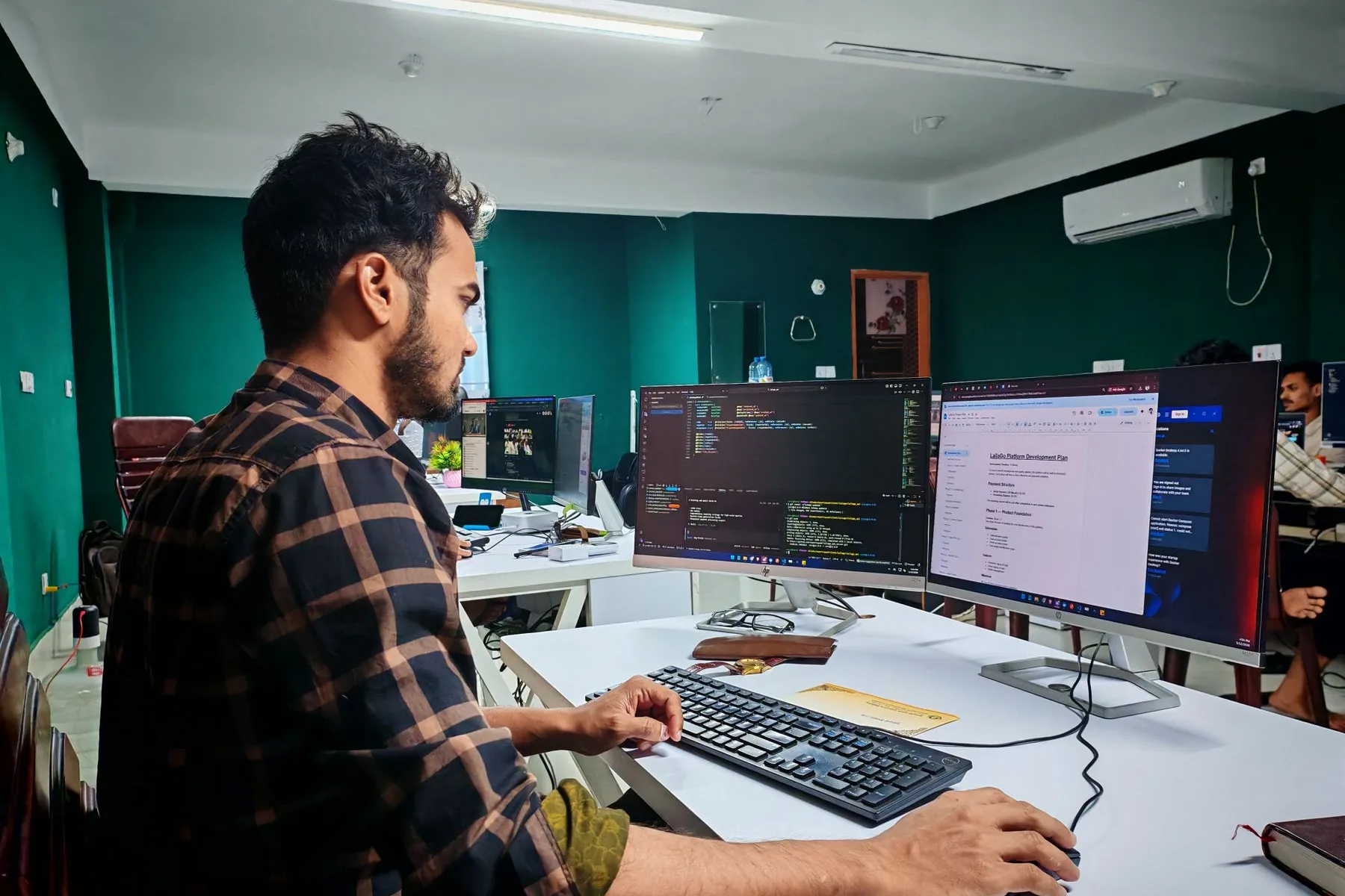 Software developer working on code at two monitors in an office