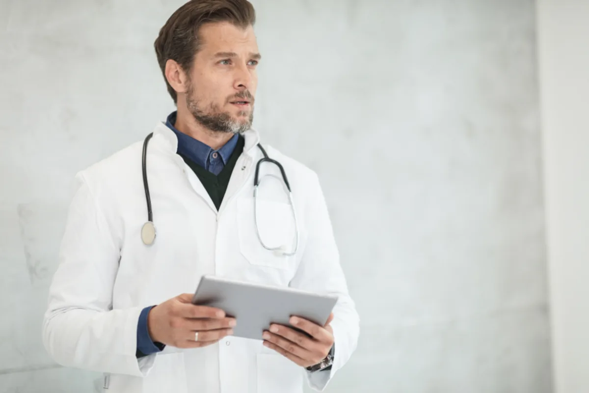 Doctor in a white coat holding a tablet