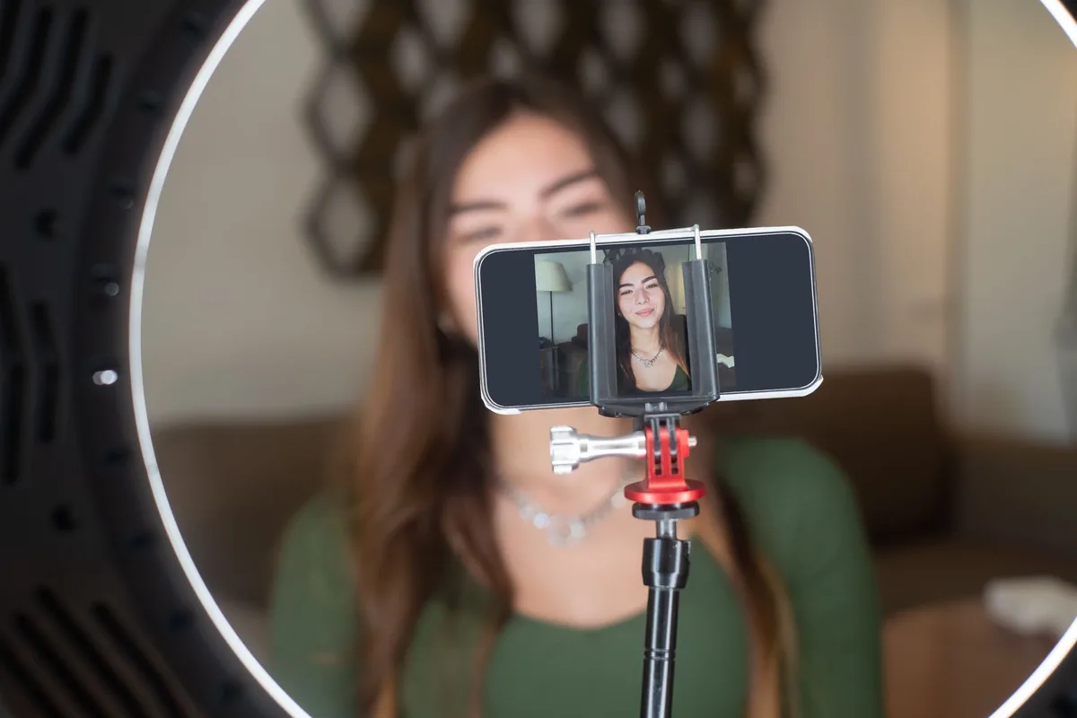 Young woman live streaming from home with a smartphone and ring light