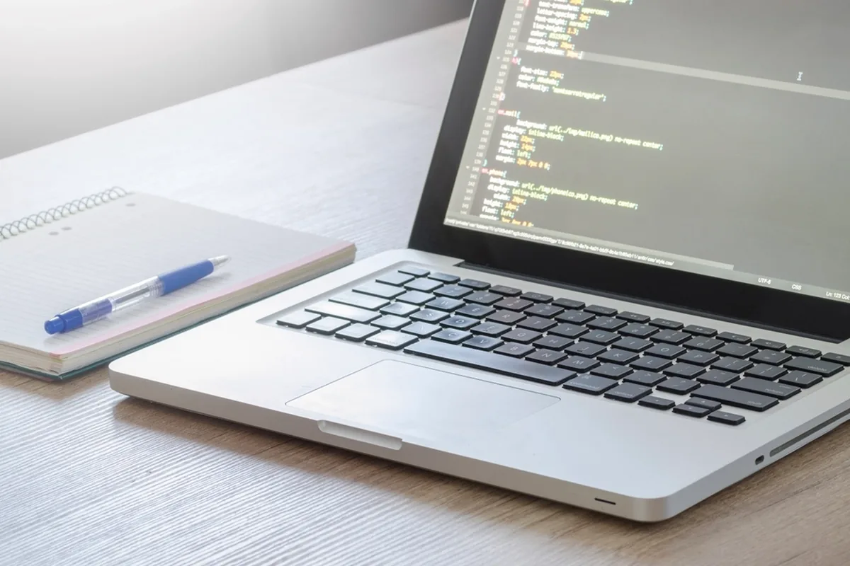 Laptop showing website code on a desk