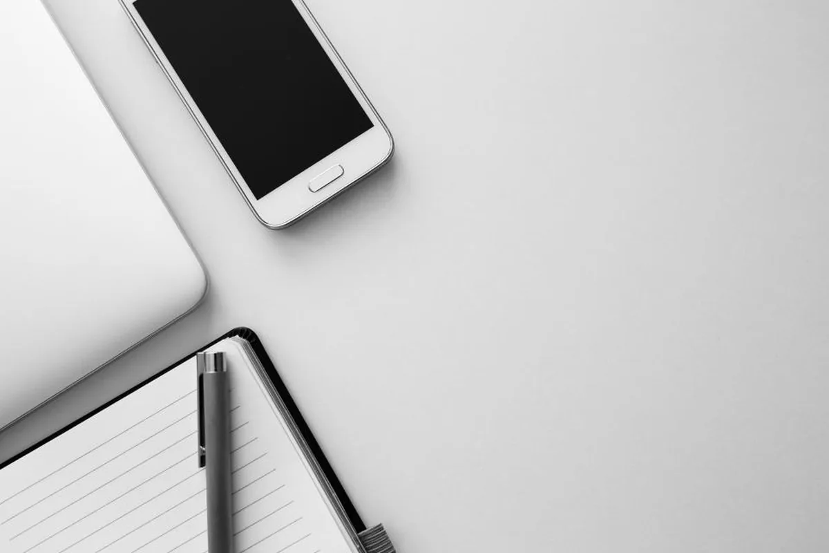 Smartphone, laptop and notebook on a desk, representing mobile apps built for US companies